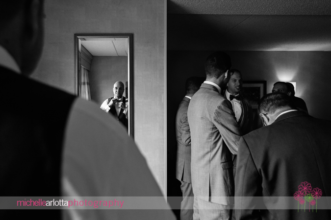 groom adjusting tie in mirror