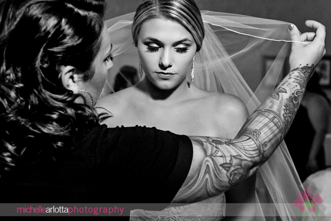 tattooed hairstylist putting veil on bride