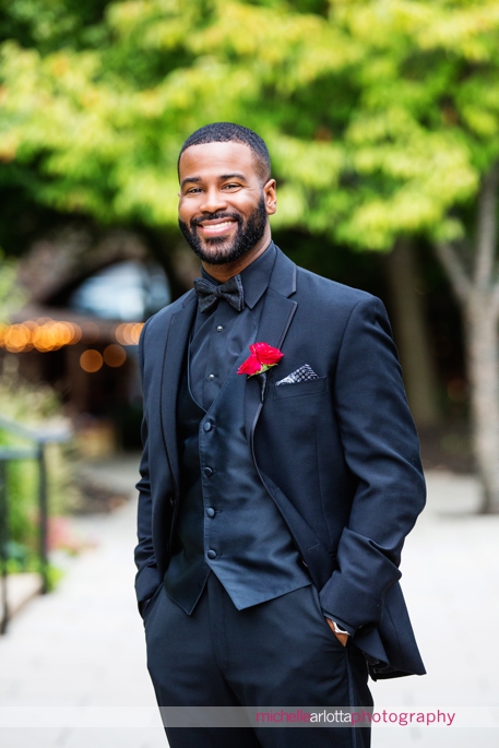 African american groom in black suit with black shirt and red rose by Alisha Simone