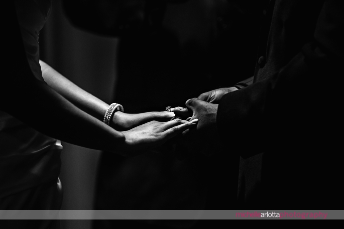 bride and groom holding hands in dramatic light during indoor wedding ceremony at Nassau Inn in Princeton, NJ photographed by michelle Arlotta photography