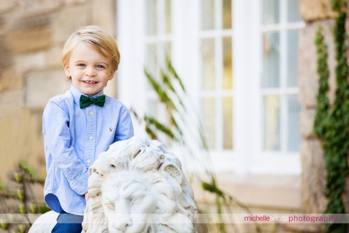 toddler with bowtie smiles for the camera during family photography session in New Jersey