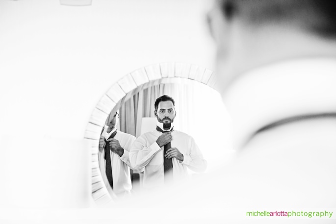 groomsmen adjust ties in mirror