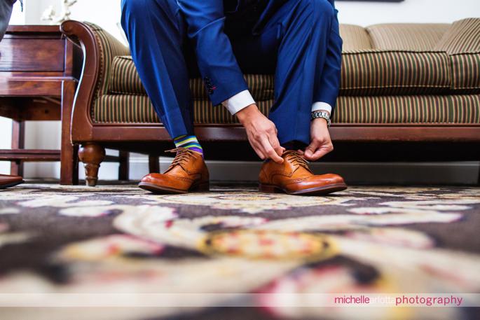 groom with blue suit and striped socks ties shoes for his battleground country club wedding