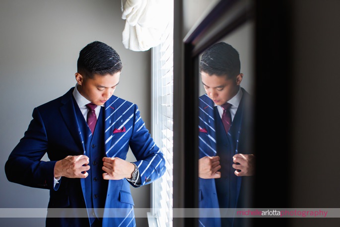 groom in blue suit with maroon tie and detailing adjusts his jacket at battleground country club