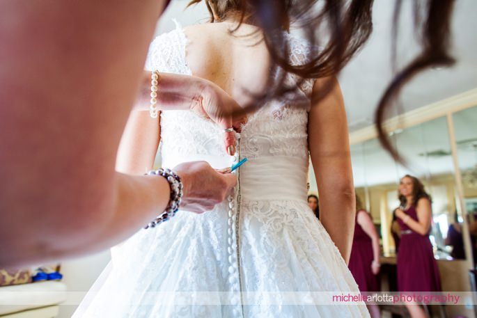 maid of honor uses crochet needle to button 3graces bridal wedding dress at batteground country club