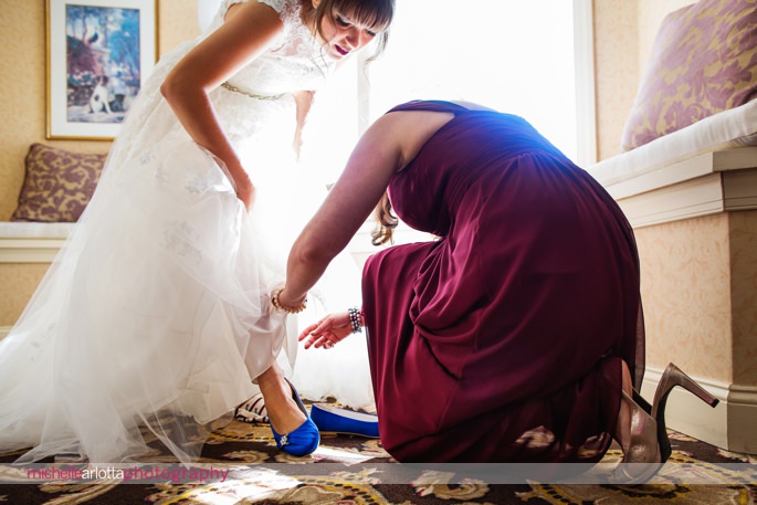 maid of honor in maroon dress helps bride with blue shoes