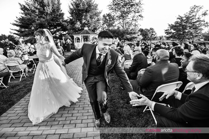 groom low fives as he exits wedding ceremony with bride at the battleground country club