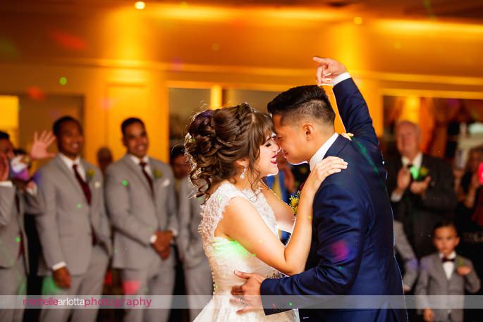 bride and groom kiss as groom raises right fist up in the air during their first dance at the battleground country club