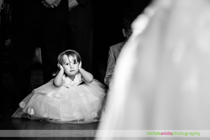 flower girl sits on floor with hands over her ears during first dance at battleground country club wedding reception