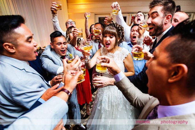bride and guests do shots during wedding reception photographed by New Jersey wedding photographer Michelle arlotta