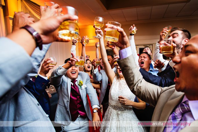 bride and guests do shots during wedding reception photographed by New Jersey wedding photographer Michelle arlotta