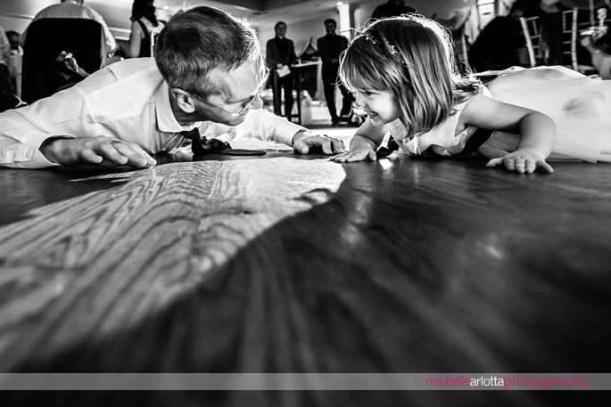 flower girl and her dad lie on the dance floor together during wedding reception at battleground country club photographed by michelle Arlotta photography
