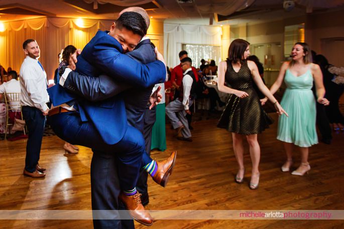 groom jumps up and hugs wedding guest during reception with mc crew at battleground country club in nj