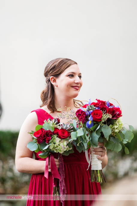 bridesmaid in red dress smiles during outdoor fall wedding ceremony at brotherhood winery