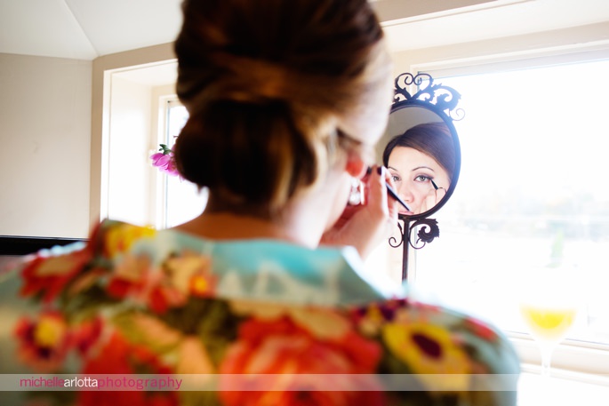 bridesmaid in floral robe does makeup in mirror at lake mohawk country club wedding nj