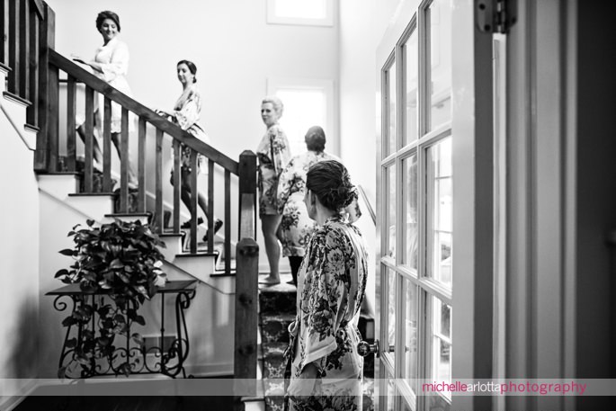bridesmaids in floral robes ascend up the staircase at the lake mohawk country club