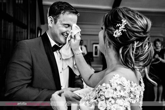 bride wipes cake from grooms face during Sussex county New Jersey wedding at lake mohawk country club photographed by michelle Arlotta photography