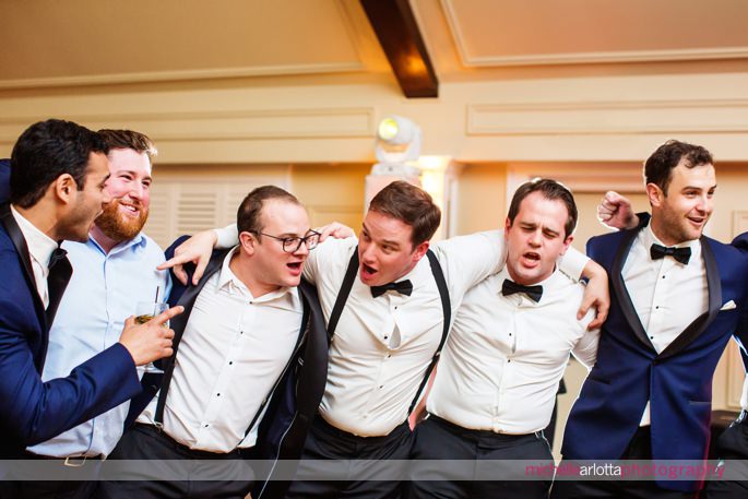 groom and groomsmen line up with arms around one another and sing during lake mohawk country club wedding reception