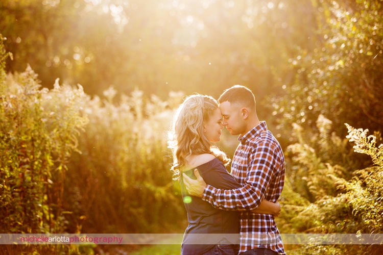 bear brook valley wedding couple embraces during New Jersey fall engagement session golden hour warm sun flare