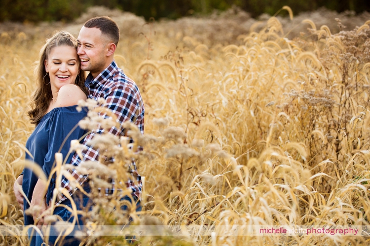 couple smiling among field of wheat during fall New Jersey engagement session