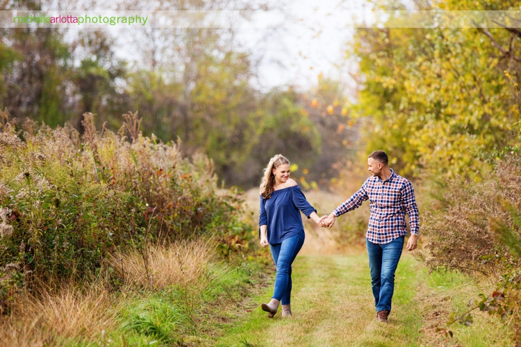 couple walks hand in hand during fall engagement session in nj