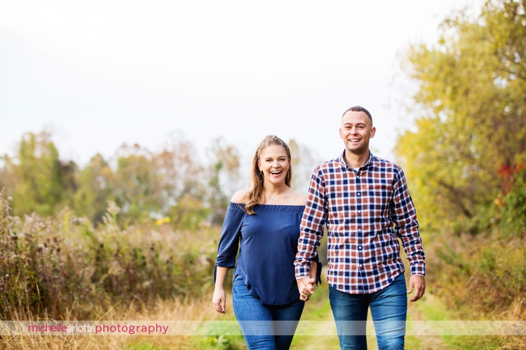 couple walks hand in hand during fall engagement session in nj
