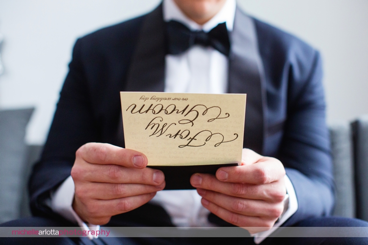groom in tuxedo reads card from bride for nj wedding