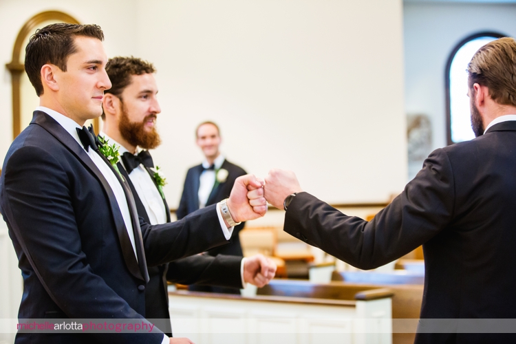 groom in tuxedo fist bumps groomsmen at altar for nj winter wedding