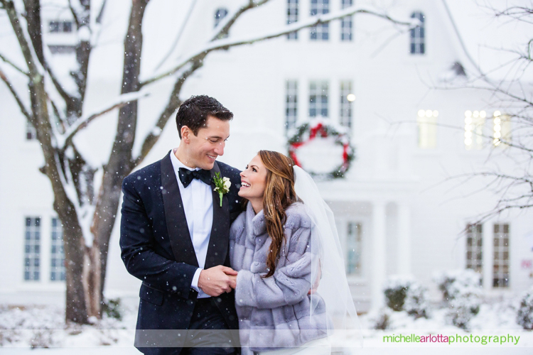 bride and groom walk together in snow during portraits at Ryland inn coach house winter wedding with New Jersey wedding photographer Michelle Arlotta photography
