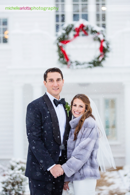 bride and groom walk together in snow during portraits at Ryland inn coach house winter wedding with New Jersey wedding photographer Michelle Arlotta photography