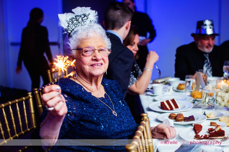 grandmother holds sparkles at table at new year's eve nj wedding reception