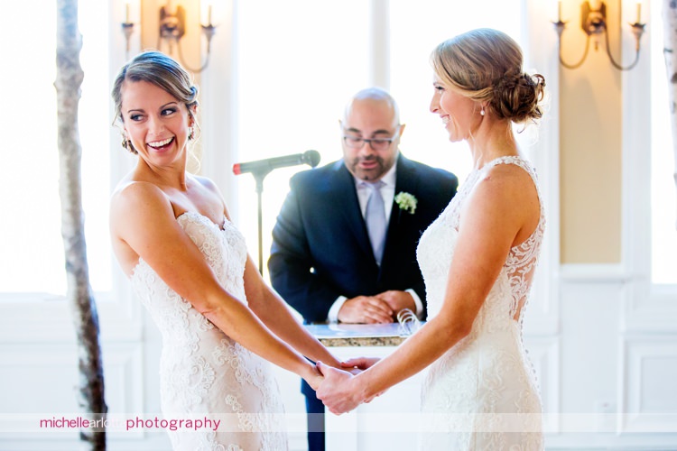 brides at altar smiling and holding hands inside at rock island lake club