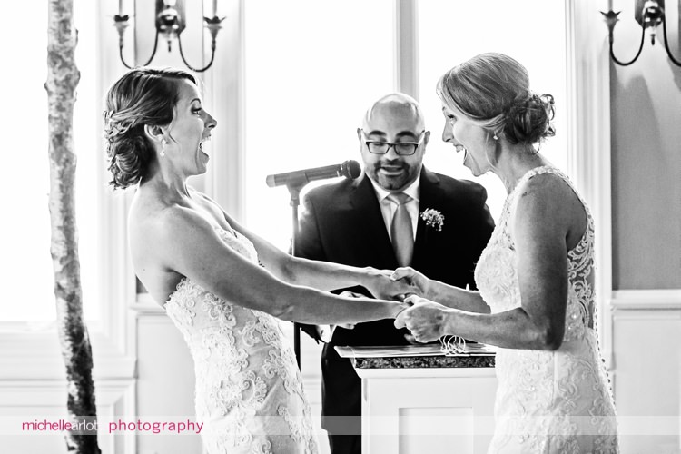 brides holding hands and reacting with glee as they are announced as wife and wife during indoor New Jersey rock island lake club winter wedding
