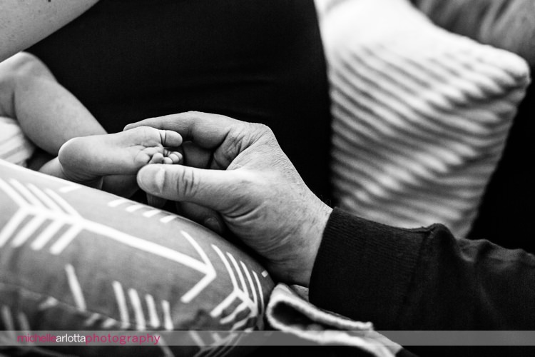 father touches newborn daughter's feet while she nurses