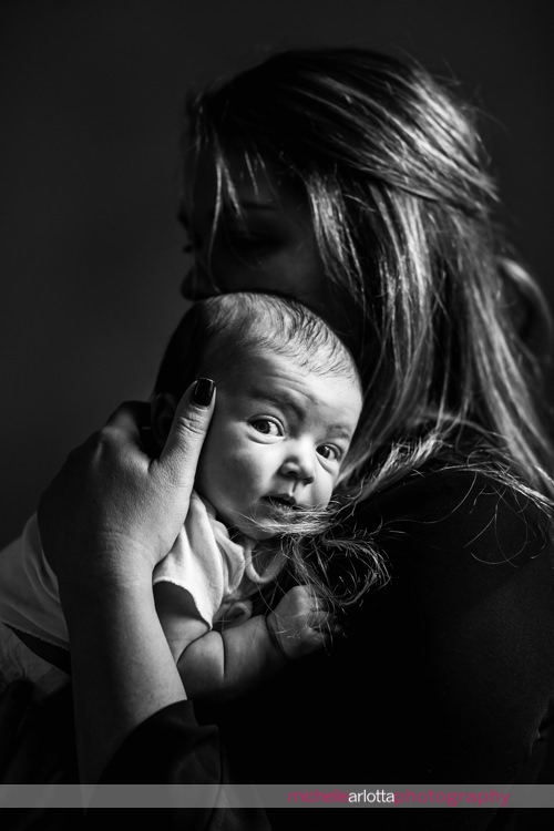 New Jersey newborn baby girl looks as camera while mother holds her