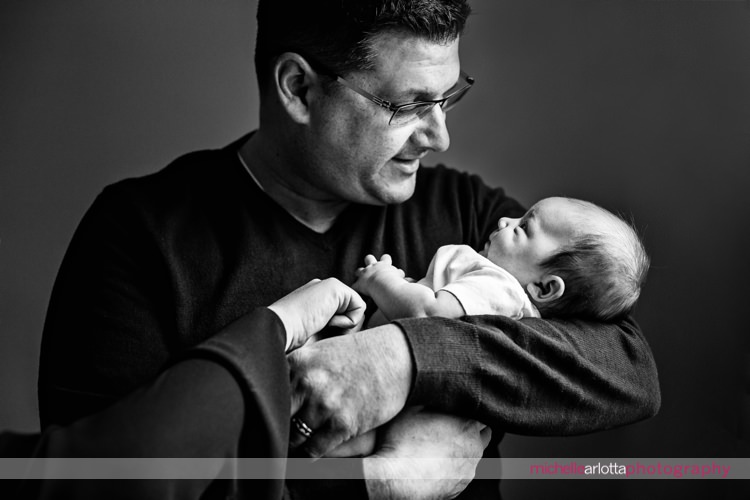 father and newborn baby daughter look at one another