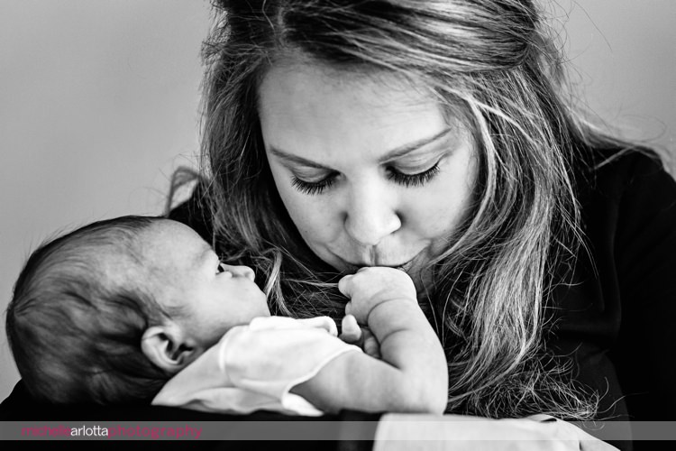 mother kisses newborn baby's hand in New Jersey