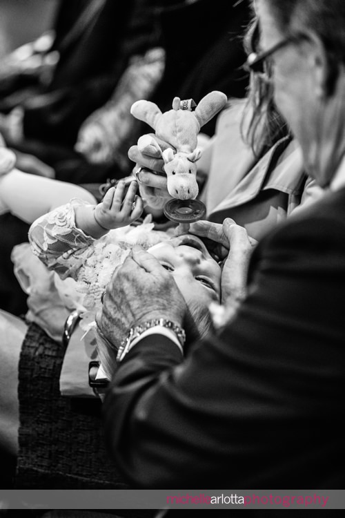 wedding guests play peek-a-boo with a baby during wedding ceremony at St Charles Borromeo Church in skillman, NJ