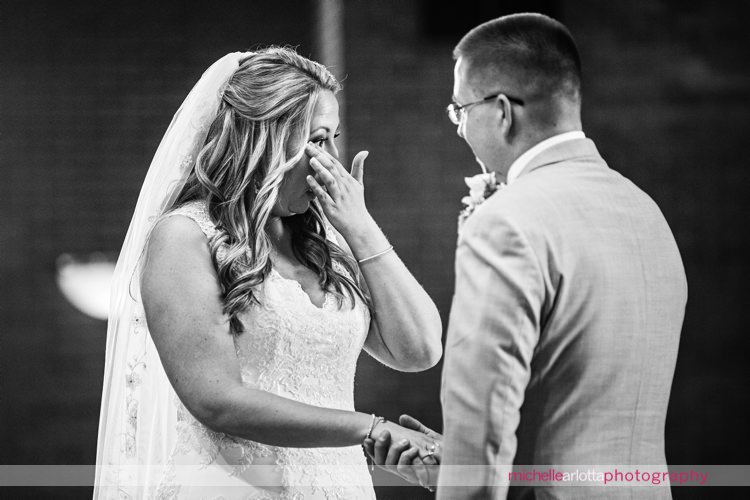 bride wipes away tear during wedding ceremony at St Charles Borromeo Church in skillman, NJ