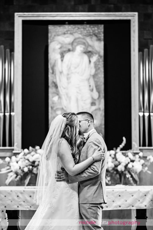 bride and groom kiss during wedding ceremony at St Charles Borromeo Church in skillman, NJ
