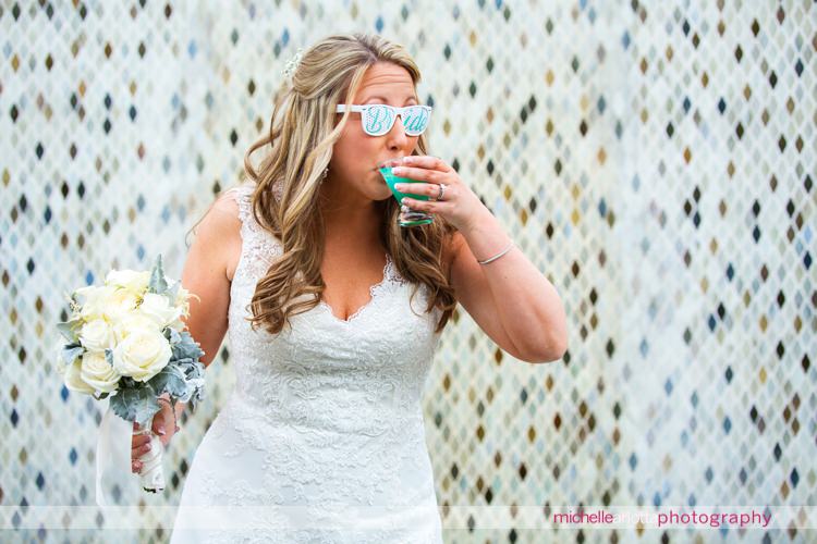bride wearing bride sunglasses drinks blue speciality drink at the grand marquis in old bridge, New Jersey