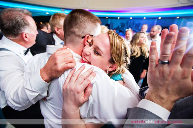 sister of the groom hugs groom at end of the night at grand marquis capture by award winning New Jersey wedding photographer Michelle Arlotta