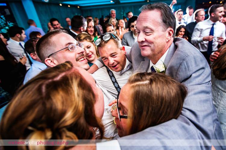 groom and his family huddle together at end of grand marquis wedding reception
