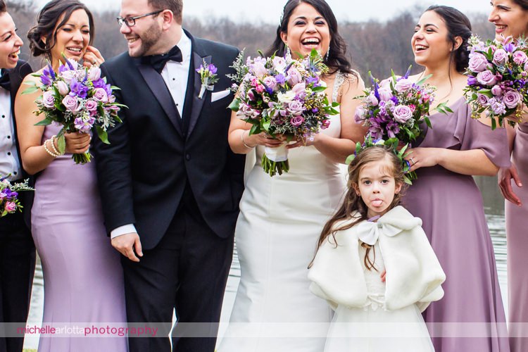 flower girl sticks out tongue while bridesmaids in shades of purple brideside bridesmaids dresses laugh