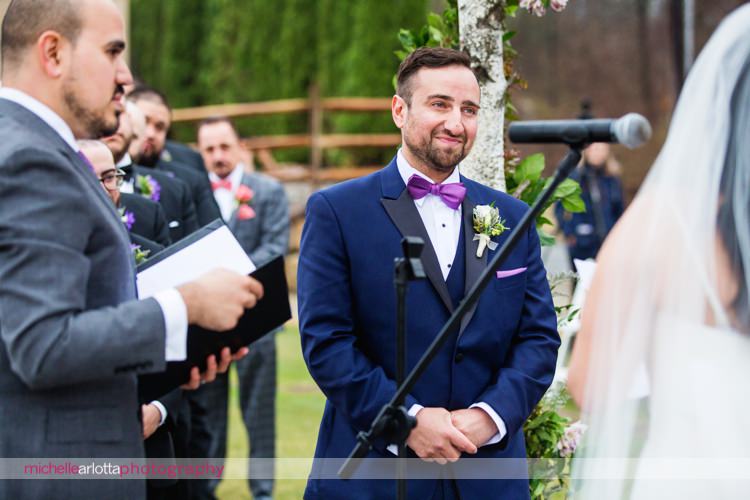 groom in blue suit and purple bowtie during outdoor nj wedding ceremony