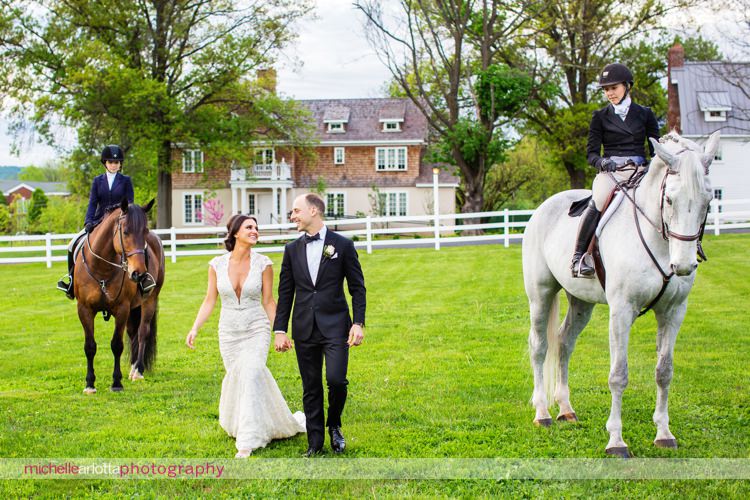 bride wearing berta wedding gown walks with groom at Ryland inn with horses in New Jersey