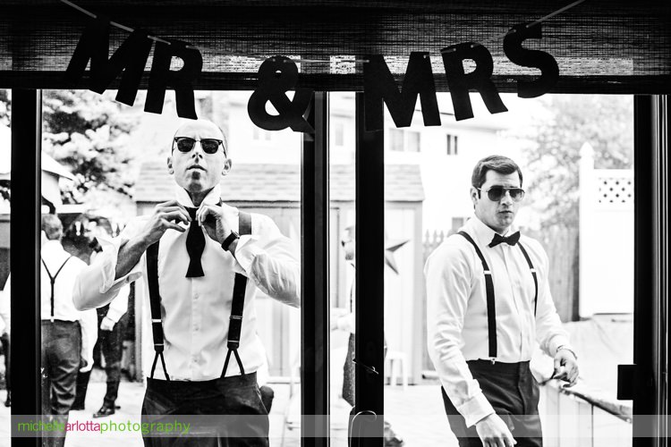 groom ties bow tie in reflection of sliding glass door for Ryland inn wedding