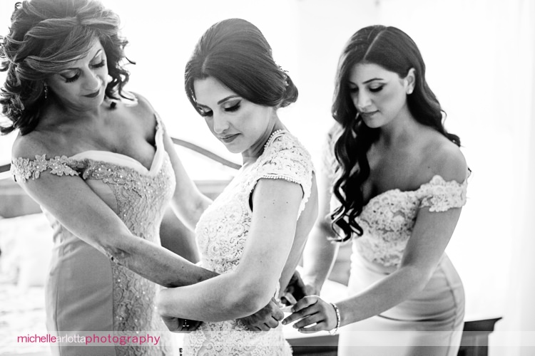 mother and sister help bride with her berta wedding dress