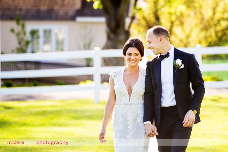 bride wearing berta wedding gown walks with groom during their spring coach house wedding at the Ryland inn in nj