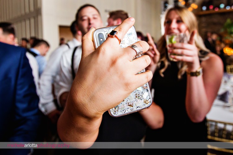 close up of wedding guest taking selfie with their phone at coach house wedding reception at Ryland inn in nj